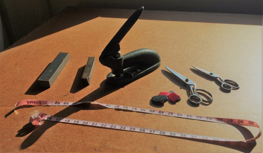 Sunlit cutting table with measuring table, scissors, weights, and a large stapler.